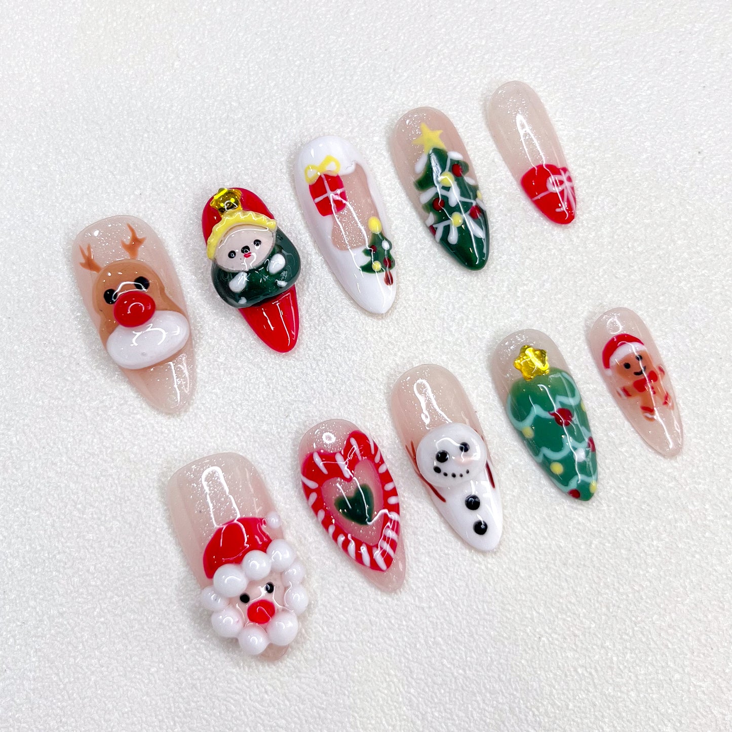 Playful Christmas press-on nails with reindeer, elf, Santa, snowman, candy cane, Christmas tree, and gift box designs.