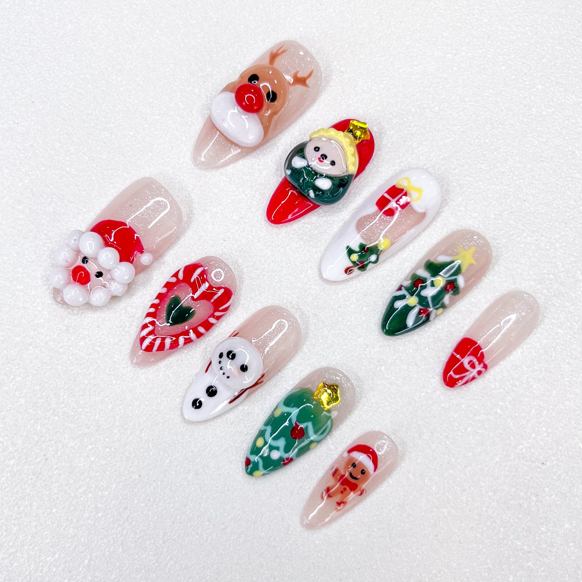 Playful Christmas press-on nails with reindeer, elf, Santa, snowman, candy cane, Christmas tree, and gift box designs.