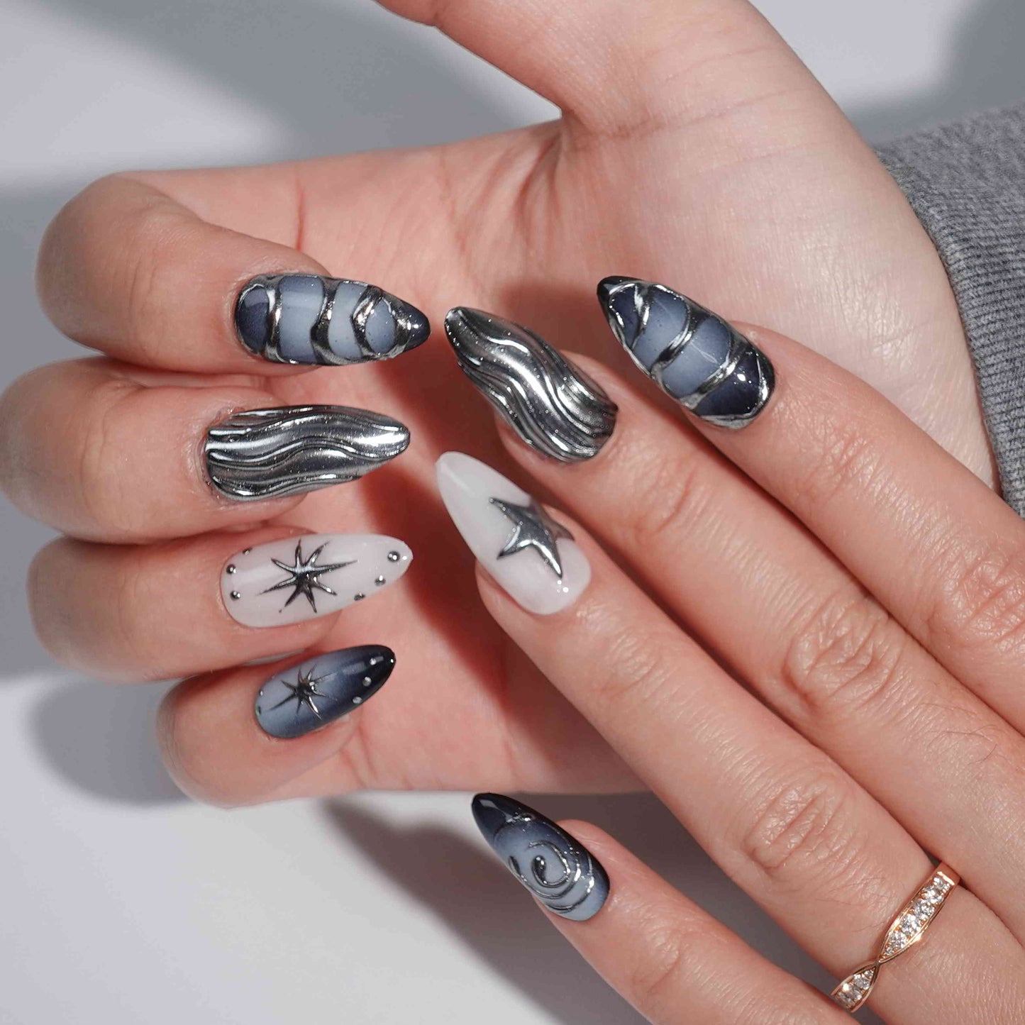 A set of press - on nails with dark blue and silver wave patterns like cosmic designs, and star - shaped accents. The nails have a celestial and stylish appearance, suitable for parties or futuristic - themed events.