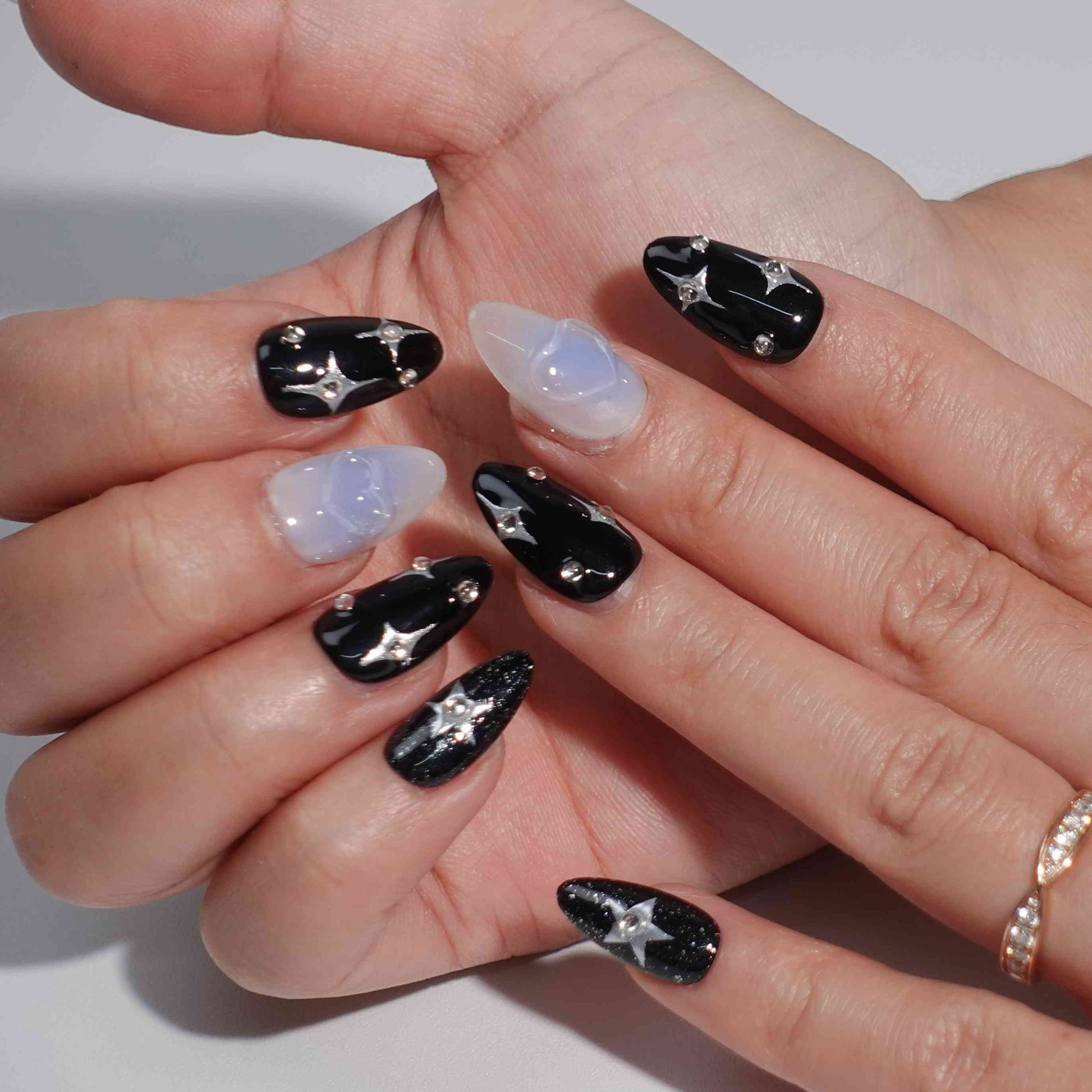 A cosmic-themed press-on nail set with a combination of black and pastel blue nails. The black nails feature glittery silver stars and rhinestones, while the blue nails include elegant bow designs. Perfect for a celestial and dreamy style.