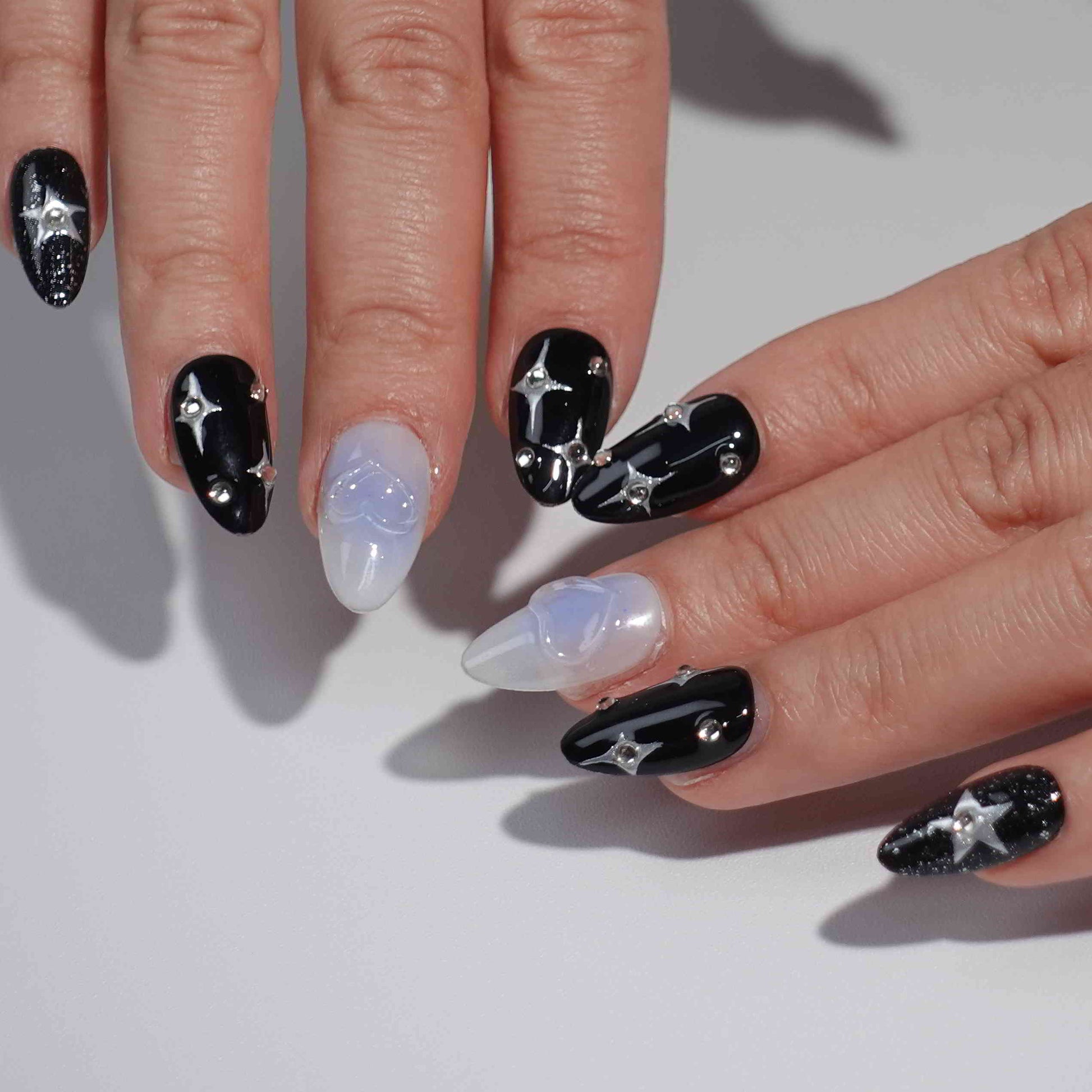 A cosmic-themed press-on nail set with a combination of black and pastel blue nails. The black nails feature glittery silver stars and rhinestones, while the blue nails include elegant bow designs. Perfect for a celestial and dreamy style.