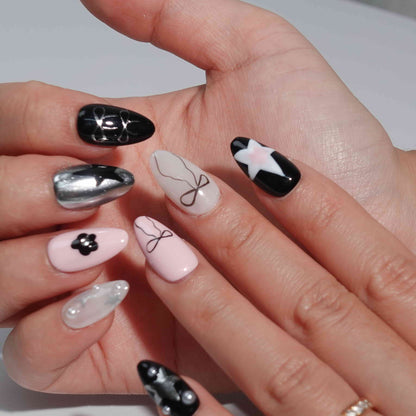 A set of press - on nails with a glamorous mix of pink and black colors, featuring stylish designs such as bows, stars, and flowers. The nails have a chic and fashionable appearance, suitable for both casual and formal events.