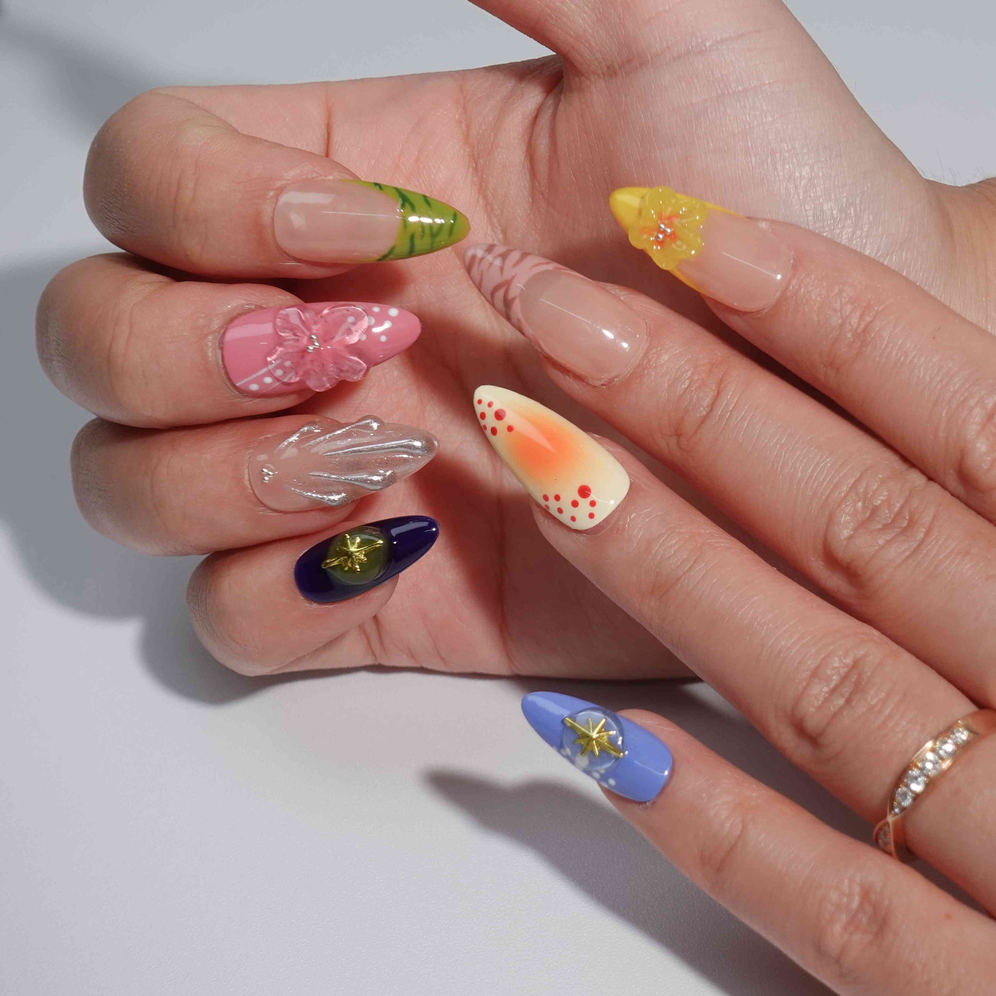 A stunning collection of press-on nails featuring intricate floral motifs, warm gradients, and elegant embellishments like gold stars and shimmer accents. Perfect for showcasing a mix of natural beauty and bold style.