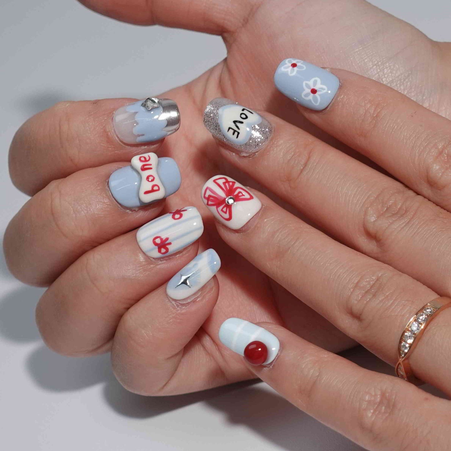 A set of press - on nails with a variety of cute and whimsical designs, including a dog, apple, heart with the word "LOVE", bow, bone, and sparkling elements, neatly arranged in a transparent case. The nails have a playful and charming finish, ideal for casual and fun - filled events.