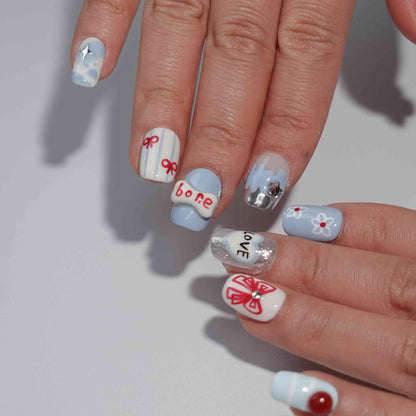 A set of press - on nails with a variety of cute and whimsical designs, including a dog, apple, heart with the word "LOVE", bow, bone, and sparkling elements, neatly arranged in a transparent case. The nails have a playful and charming finish, ideal for casual and fun - filled events.