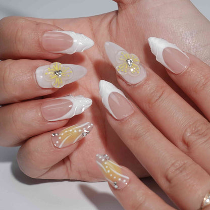 A bright and cheerful handmade set of press-on nails featuring soft yellow-to-peach gradients, 3D floral embellishments, and sparkling rhinestone details, evoking the warmth and light of a summer sunrise.