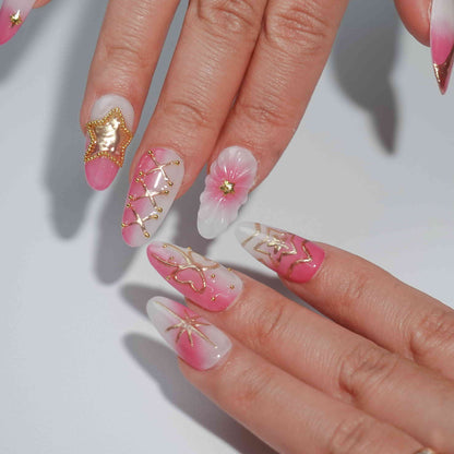 A stunning set of handmade press-on nails featuring celestial-themed designs, including golden stars, moons, and bows, with a graceful pink and white gradient.