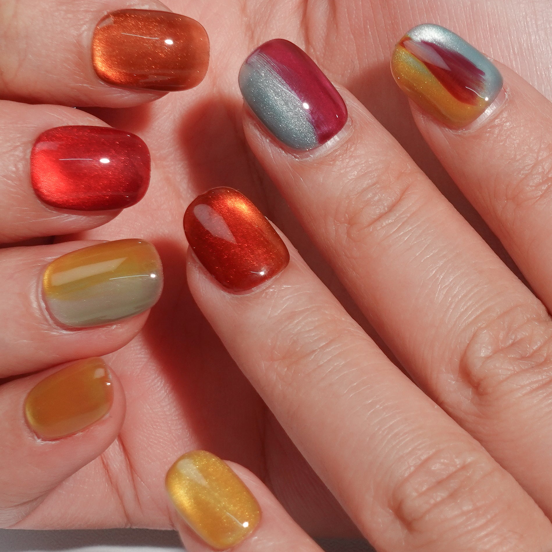 A set of press - on nails with a captivating mix of colors resembling the aurora borealis, neatly arranged in a transparent case. The nails have an iridescent, dreamy finish, ideal for making a statement at parties or creative events.