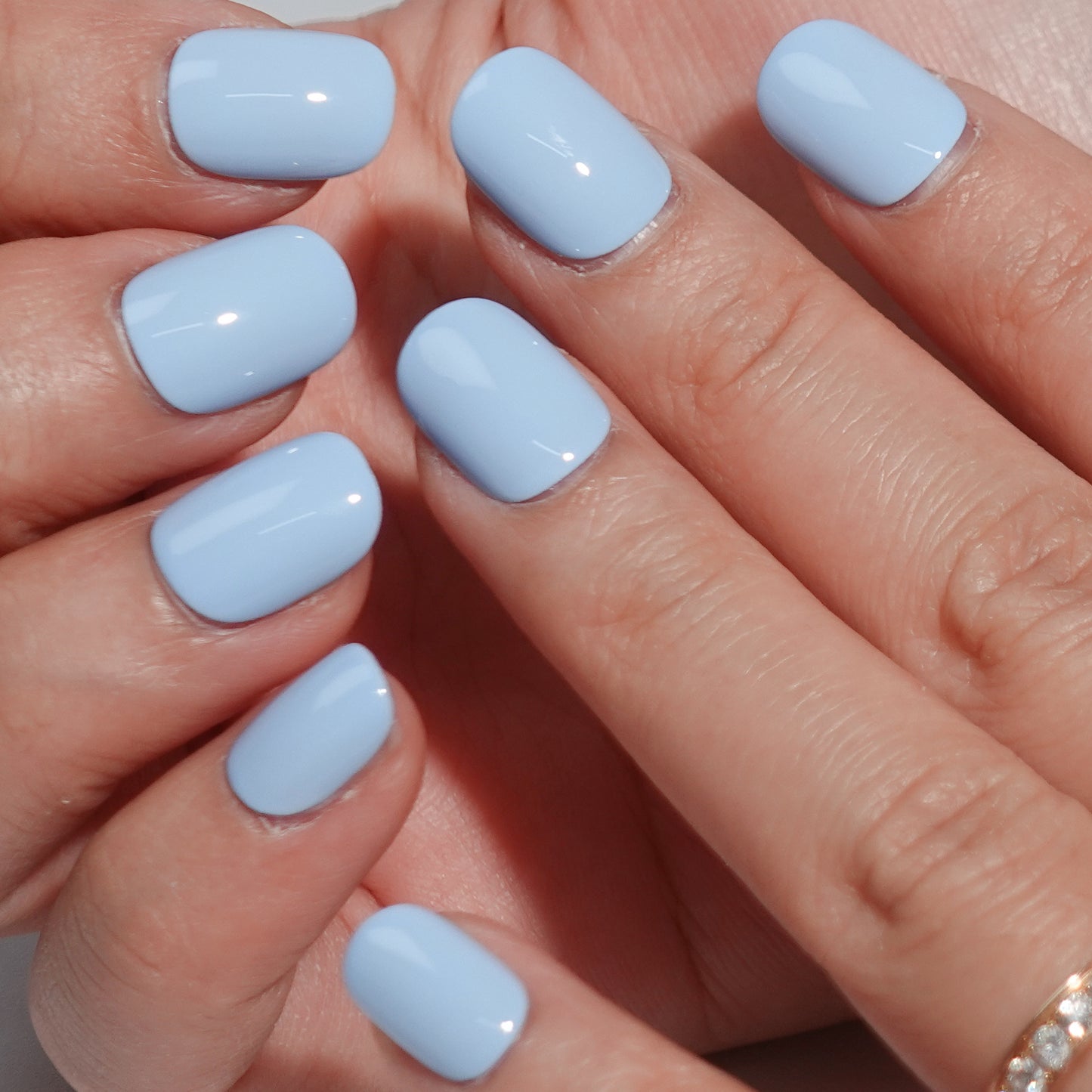 A set of light blue glossy press-on nails neatly arranged in a transparent case, featuring a natural, smooth finish, ideal for achieving a simple and elegant daily style.