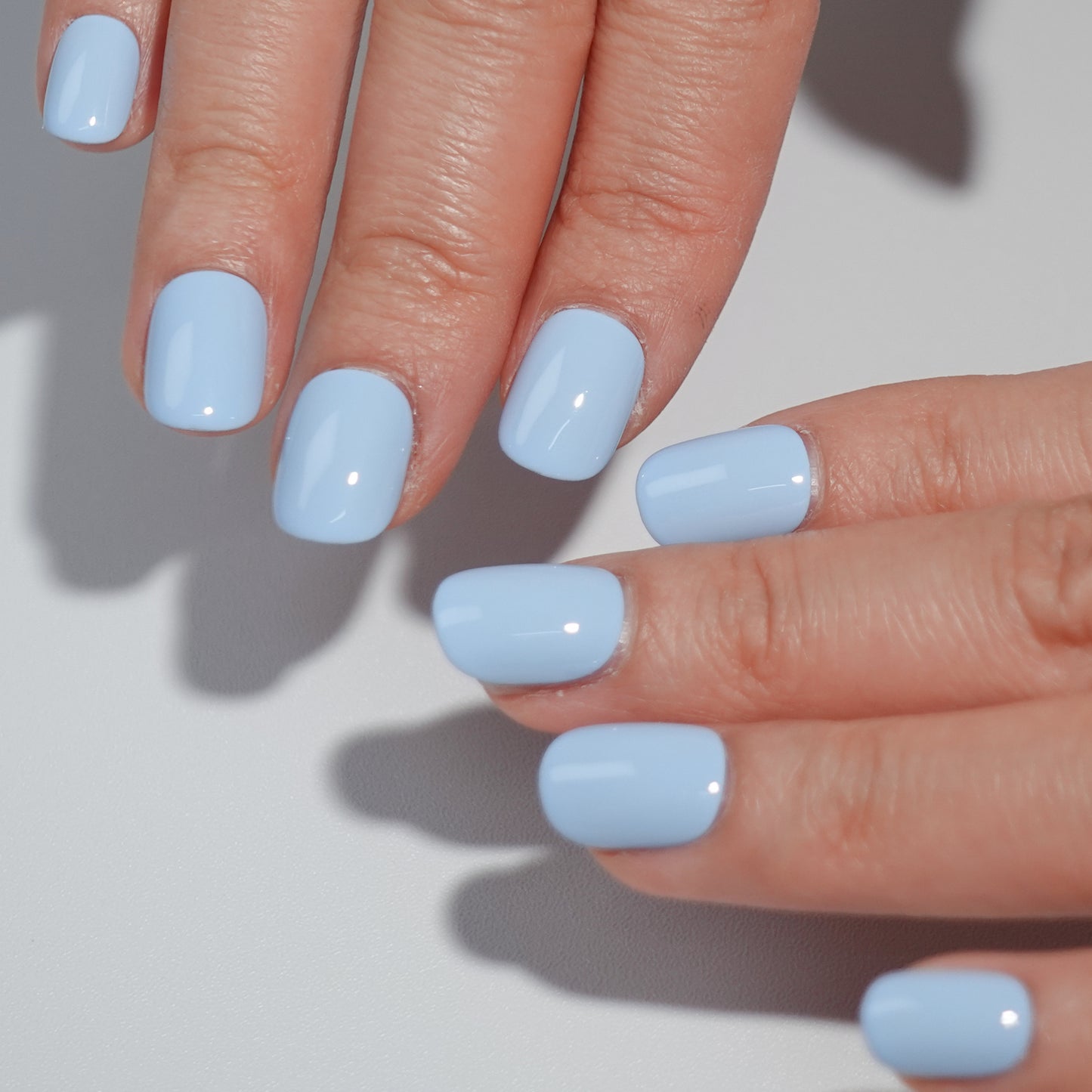 A set of light blue glossy press-on nails neatly arranged in a transparent case, featuring a natural, smooth finish, ideal for achieving a simple and elegant daily style.