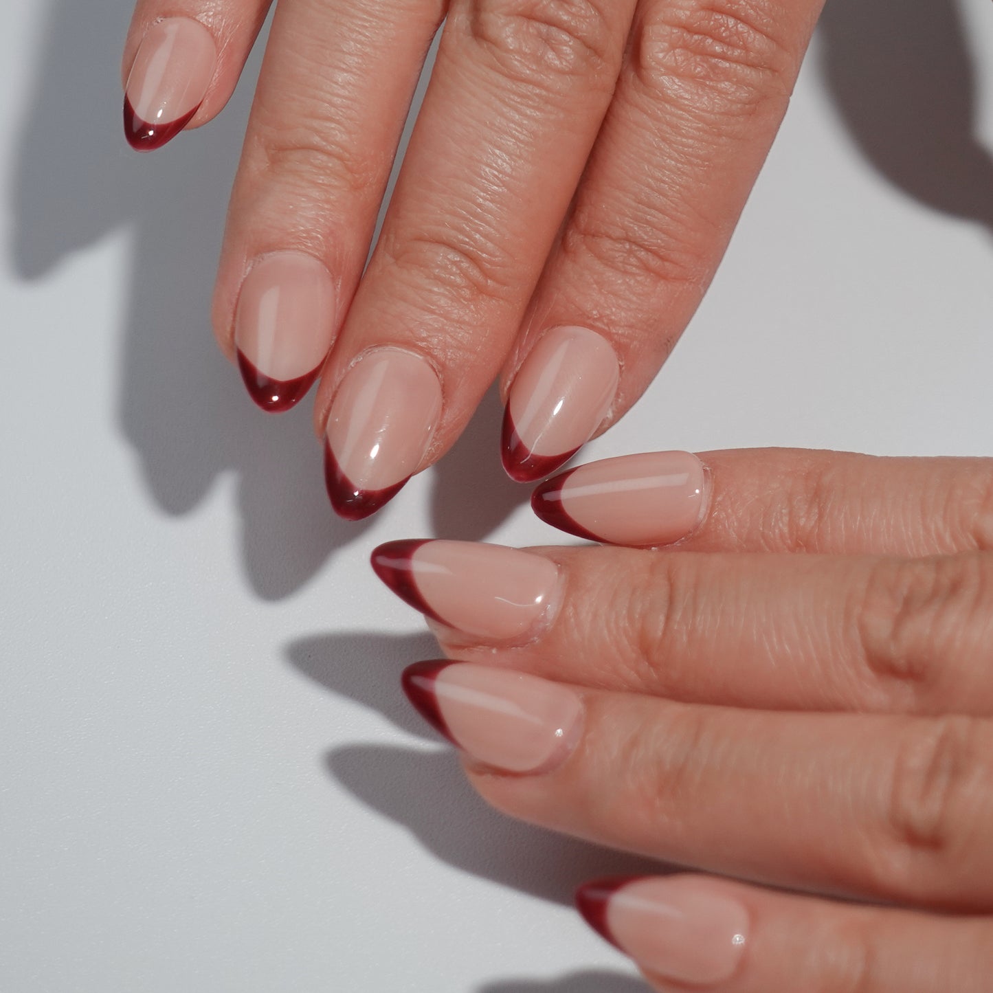 Deep brown French nails with almond-shaped design and smooth nude base, exuding noble elegance.