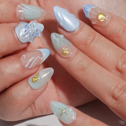 A set of handmade press-on nails showcasing soft blue and pastel gradients, detailed flower designs, starfish motifs, and pearl embellishments. These nails radiate an ocean-inspired elegance, perfect for a sophisticated and serene look.