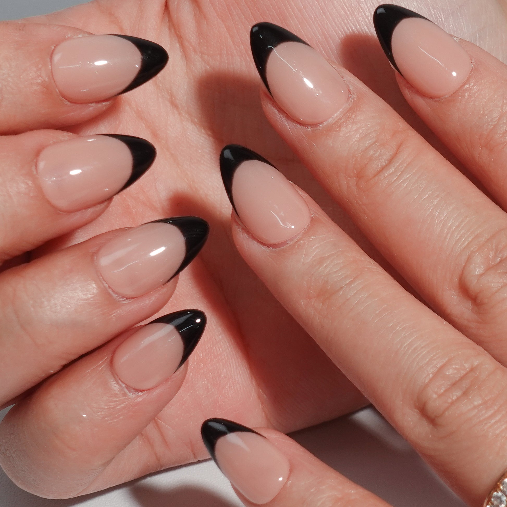 A bold nail design named "Eclipse Noir," combining nude nails with sleek black French tips. This set evokes the mystique and contrast of a lunar eclipse, offering a contemporary take on timeless elegance for evenings or formal occasions.