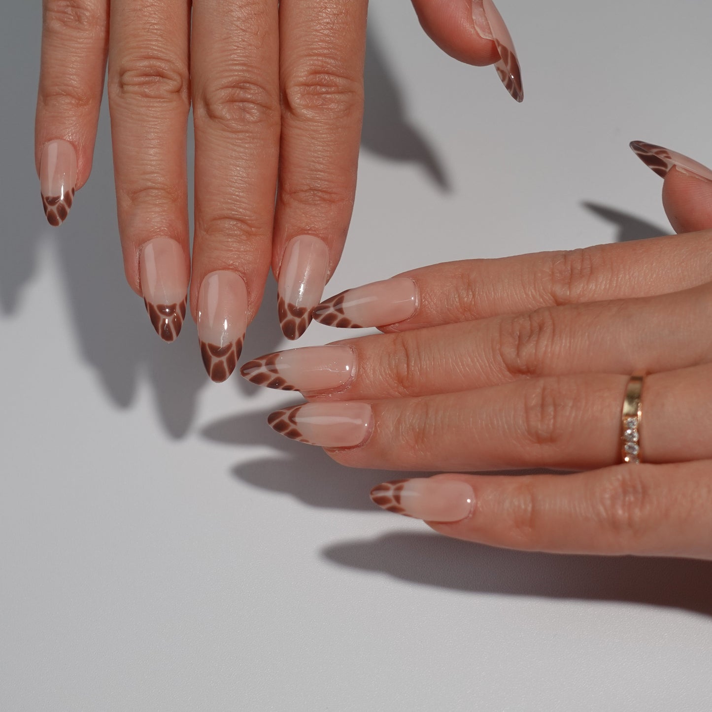 A sophisticated press-on nail set showcasing nude pink bases with deep brown French tips in a subtle leopard print pattern. This design exudes a balanced combination of chic refinement and untamed allure, ideal for adding a touch of wild charm to your look.