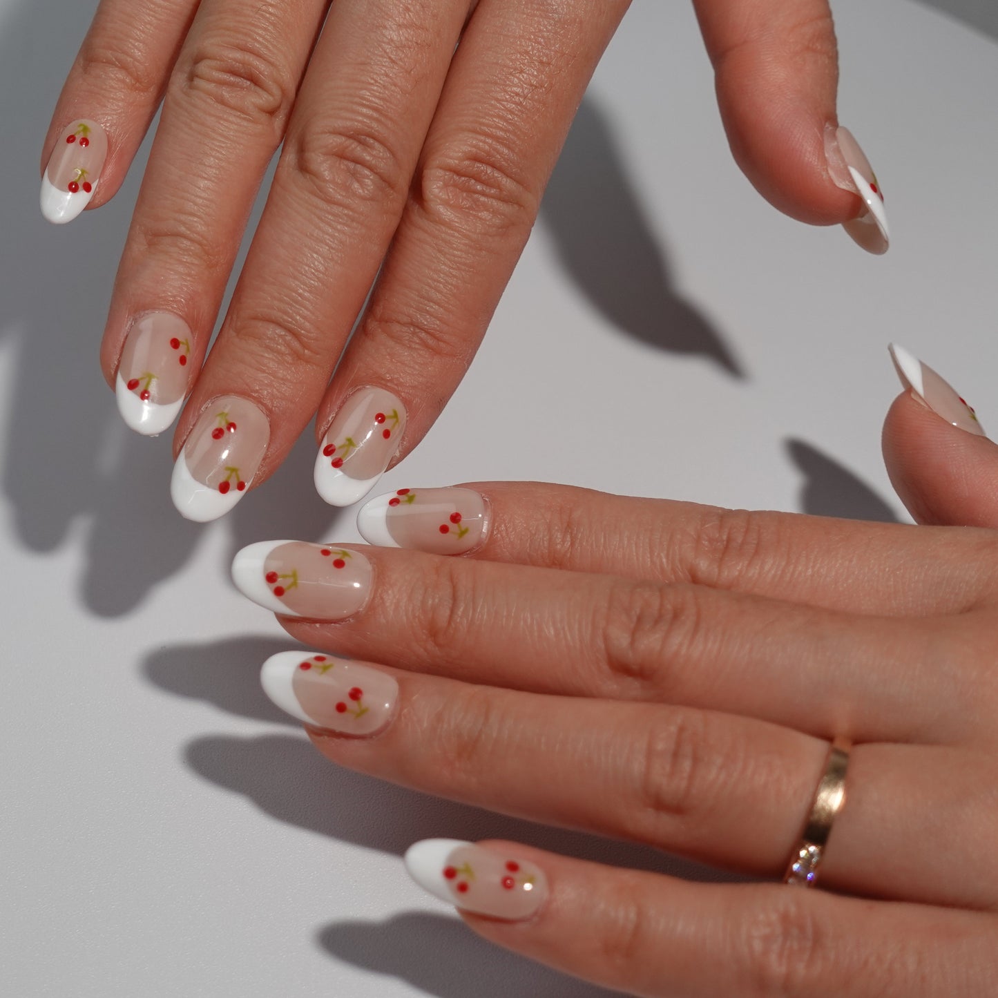 Nude nails with white French tips, beautifully decorated with dainty red cherries and green stems. This design captures the simplicity and elegance of a summer orchard, offering a graceful yet playful touch.