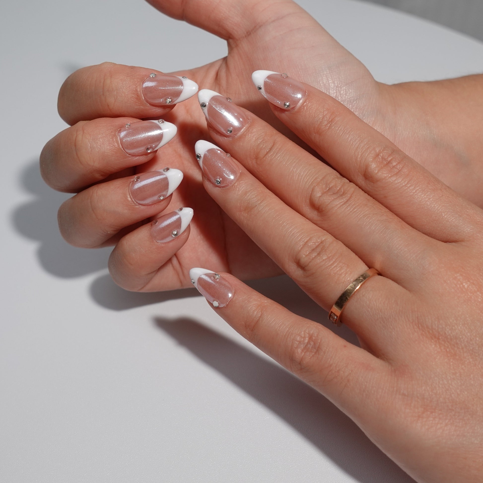 Nude nails adorned with dazzling white French tips and embellished with sparkling diamond accents. The design exudes an ethereal charm, reminiscent of moonlight reflecting on a serene lake.