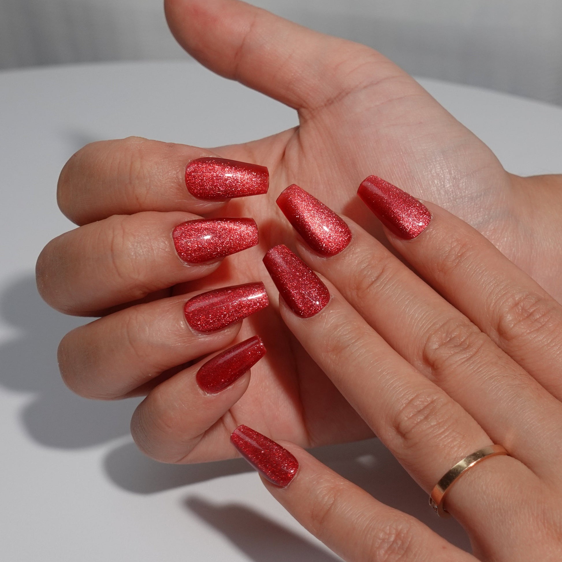 Stunning ruby red press-on nails with a sparkling glitter finish, ideal for an elegant and festive look."