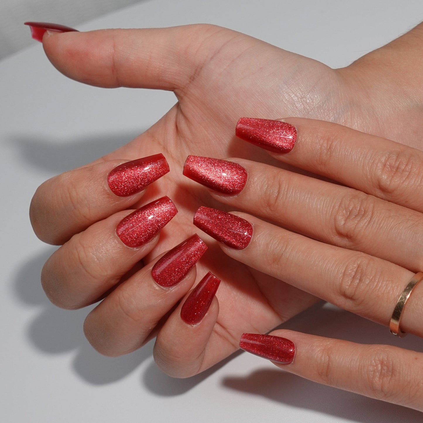 Stunning ruby red press-on nails with a sparkling glitter finish, ideal for an elegant and festive look."