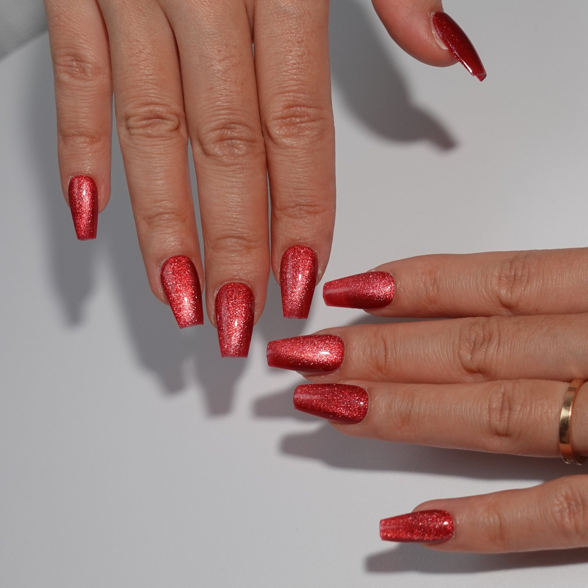 Stunning ruby red press-on nails with a sparkling glitter finish, ideal for an elegant and festive look."