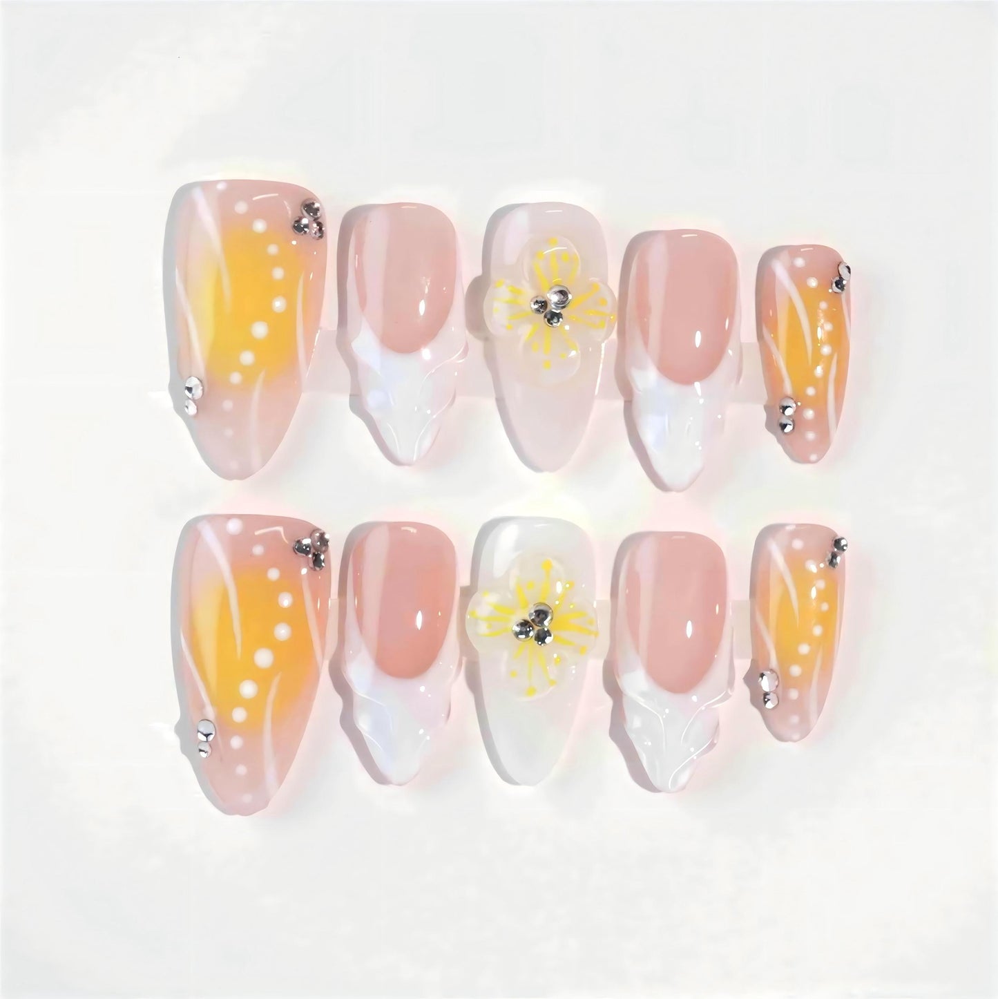 A bright and cheerful handmade set of press-on nails featuring soft yellow-to-peach gradients, 3D floral embellishments, and sparkling rhinestone details, evoking the warmth and light of a summer sunrise.