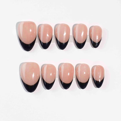 A bold nail design named "Eclipse Noir," combining nude nails with sleek black French tips. This set evokes the mystique and contrast of a lunar eclipse, offering a contemporary take on timeless elegance for evenings or formal occasions.