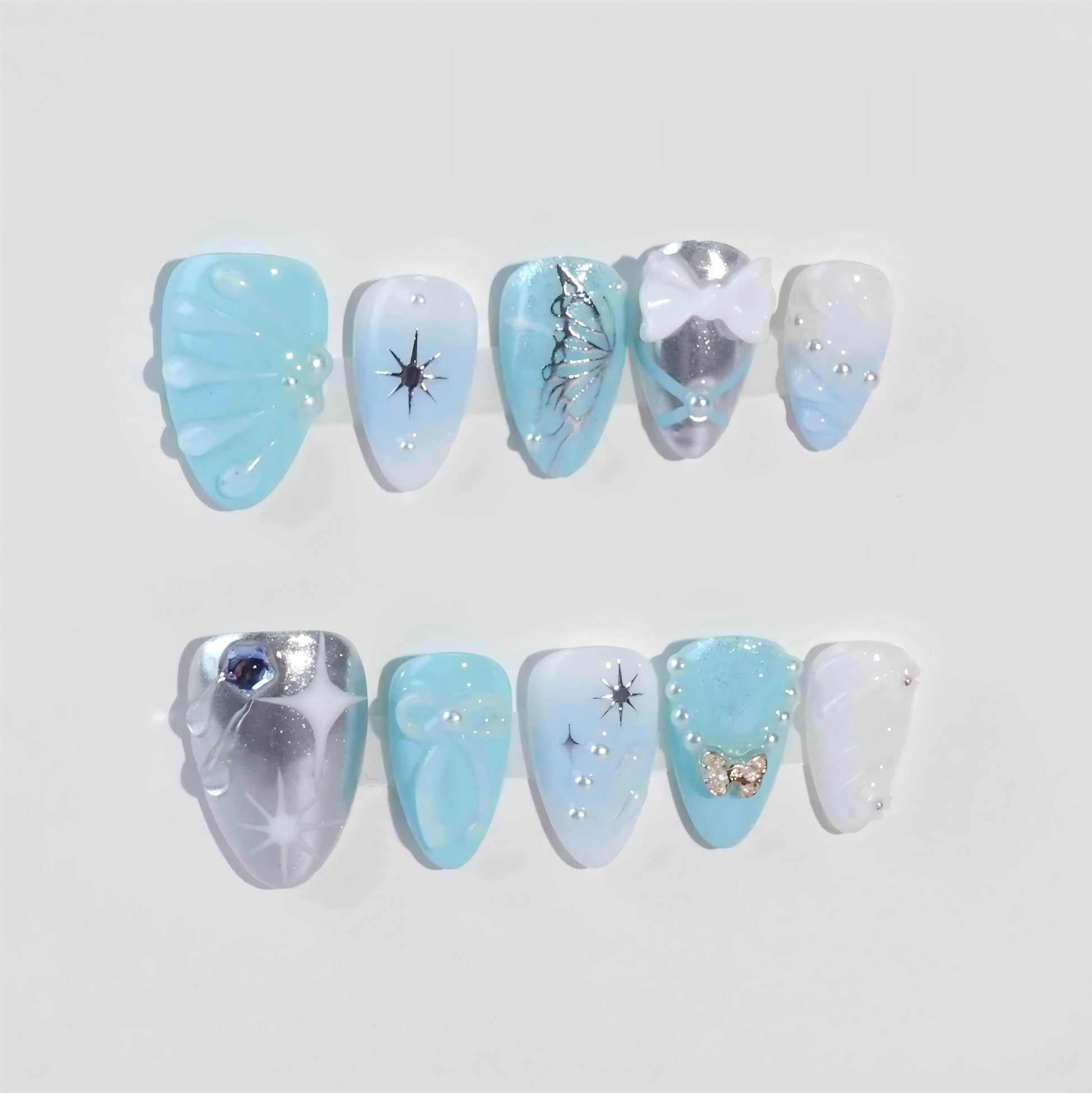 A sophisticated press-on nail design with a frosty blue color scheme, highlighted by snowflake-inspired star details, shimmering silver finishes, and delicate pearl and bow decorations. Perfect for capturing the charm of winter.