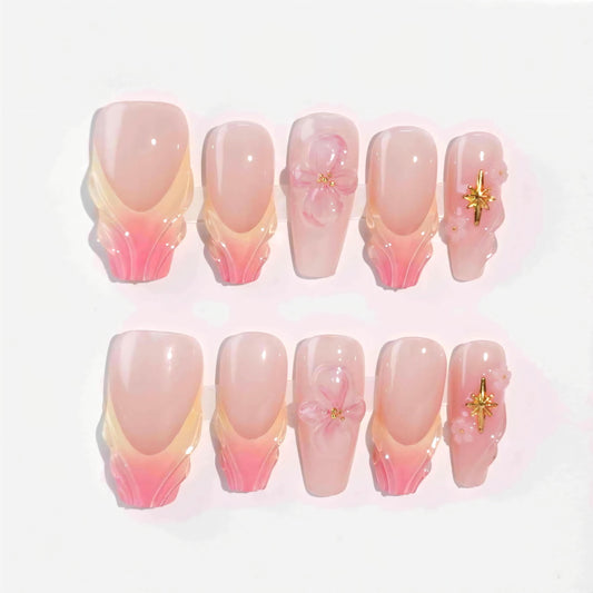 A stunning set of handmade press-on nails with soft pink gradients, beautifully sculpted petal edges, 3D flowers, and golden star decorations, evoking an elegant and dreamy aesthetic.