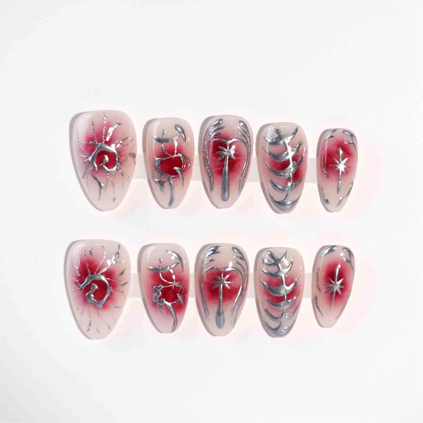 A striking press-on nail set with a red gradient background, adorned with silver metallic details, including abstract floral designs, delicate vines, and celestial star motifs. A perfect choice for a dramatic yet sophisticated look.