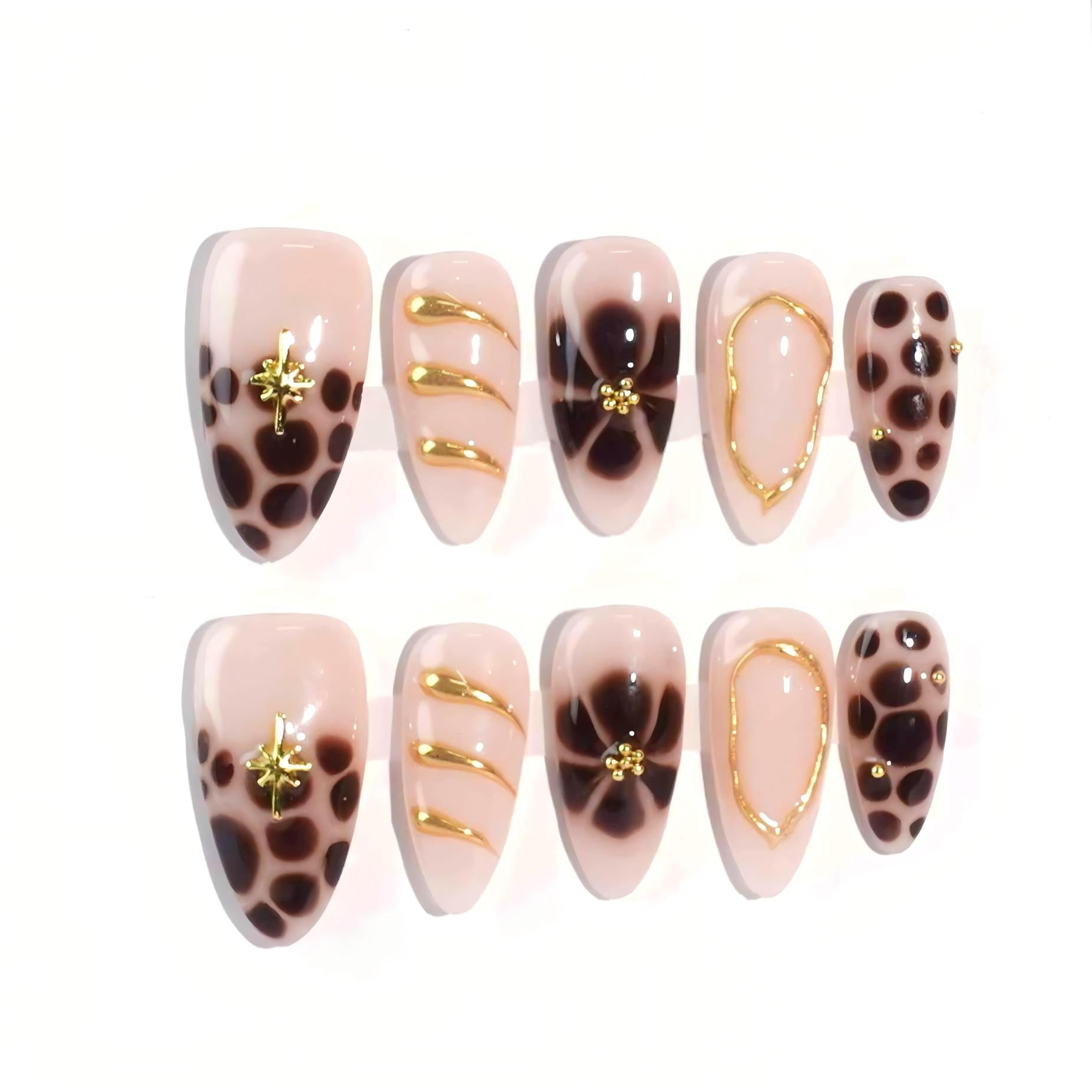 A stunning set of handmade press-on nails featuring bold brown floral prints, delicate gold embellishments, and intricate designs on a nude beige background, creating a refined yet artistic look.