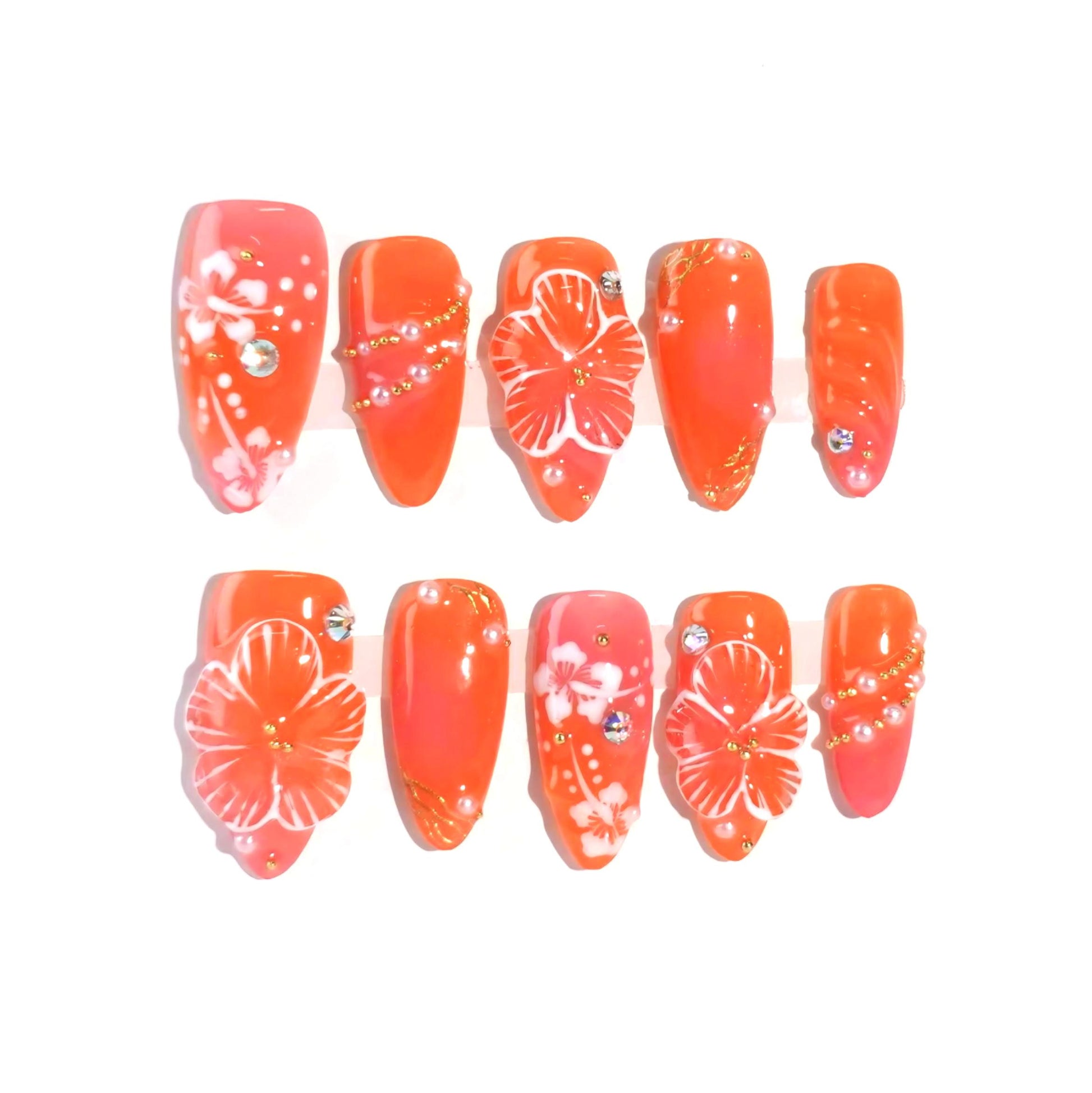 A vibrant coral press-on nail set featuring hand-painted white hibiscus flowers, sparkling rhinestones, and golden accents, evoking the warmth and beauty of a tropical getaway. Perfect for summer-inspired looks.