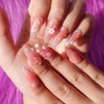 A charming set of handmade press-on nails adorned with intricate pink flowers, glittering details, and ethereal designs, radiating a soft, romantic glow.