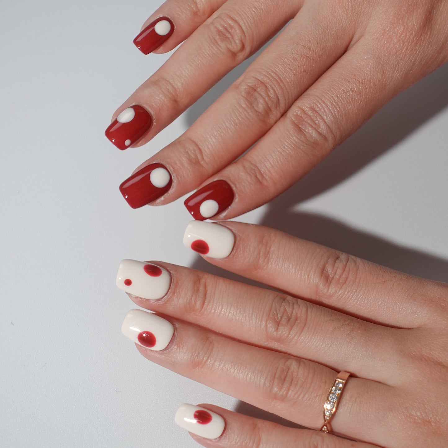 A set of press - on nails with a classic contrast of white and red, worn on a person's hand. The nails have a smooth finish with circular patterns, ideal for creating a bold and elegant appearance, suitable for both casual and formal events.