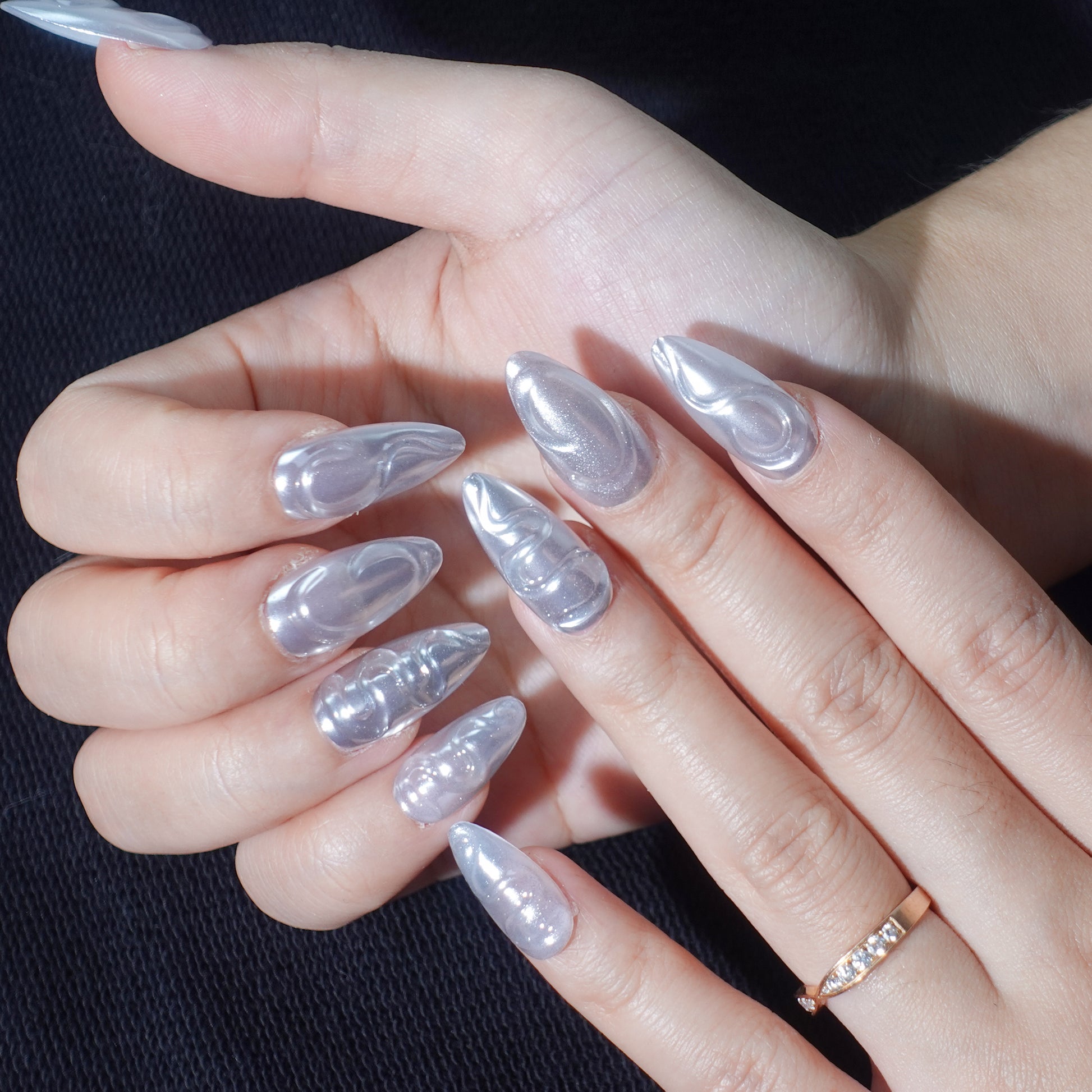 A set of press - on nails with shiny silver swirls, showcasing a sleek and modern design. The swirling patterns offer a dynamic and stylish appearance, suitable for parties or formal events.