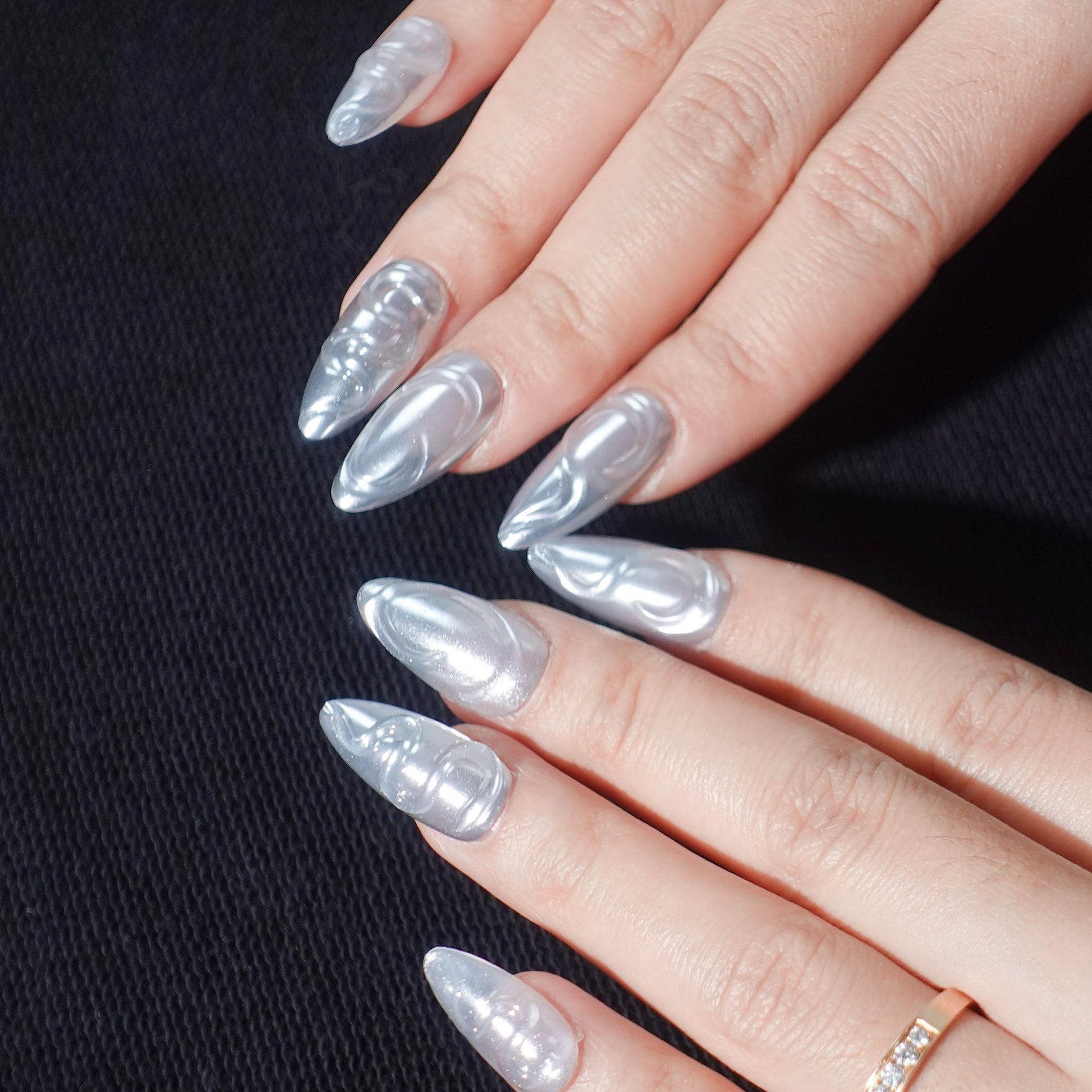 A set of press - on nails with shiny silver swirls, showcasing a sleek and modern design. The swirling patterns offer a dynamic and stylish appearance, suitable for parties or formal events.