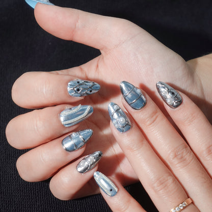 A stunning set of press-on nails in metallic blue, enhanced with silver wave patterns, delicate pearl accents, and glossy black details. This design exudes celestial grace and oceanic sophistication, perfect for an elegant and dreamy aesthetic.