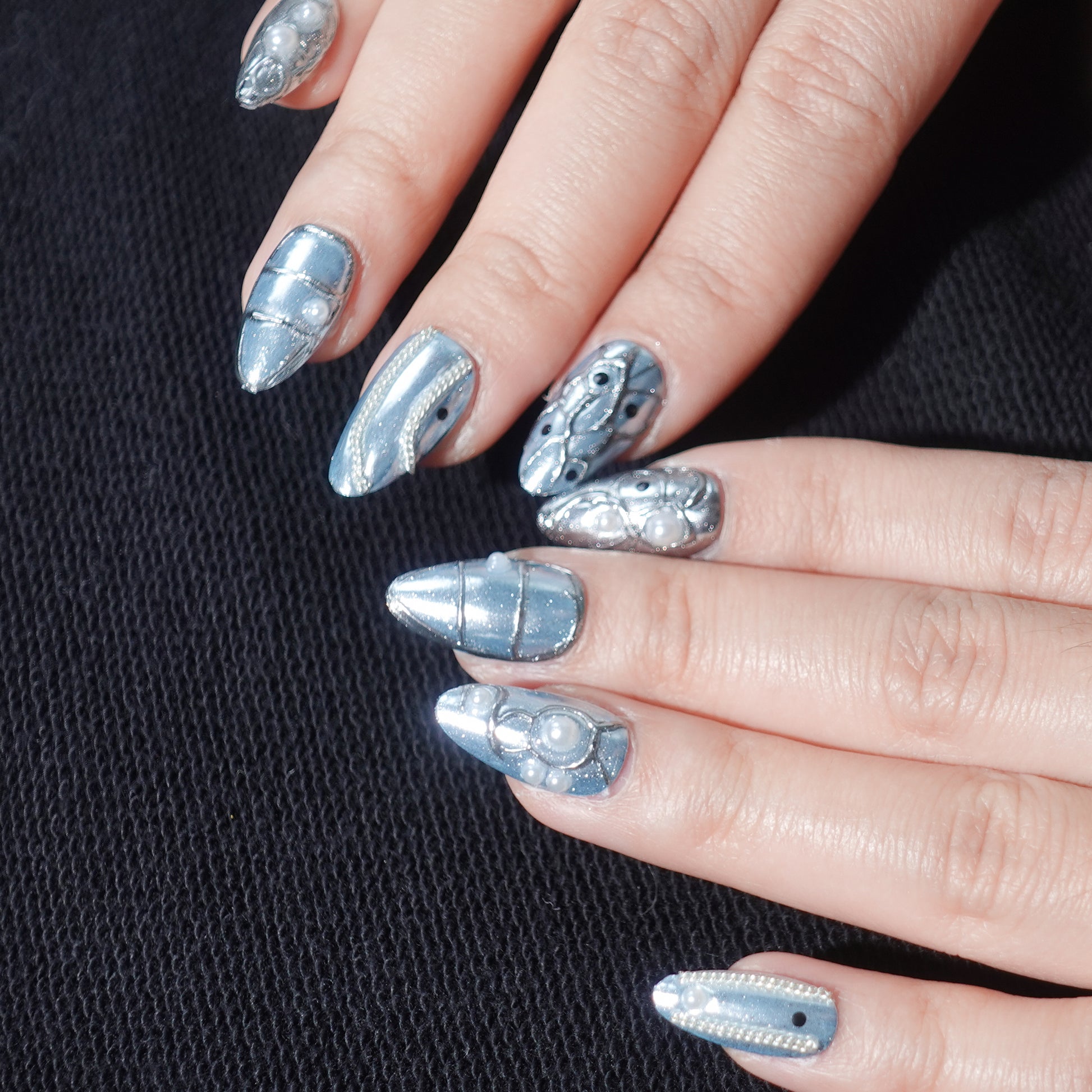 A stunning set of press-on nails in metallic blue, enhanced with silver wave patterns, delicate pearl accents, and glossy black details. This design exudes celestial grace and oceanic sophistication, perfect for an elegant and dreamy aesthetic.