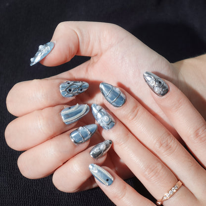 A stunning set of press-on nails in metallic blue, enhanced with silver wave patterns, delicate pearl accents, and glossy black details. This design exudes celestial grace and oceanic sophistication, perfect for an elegant and dreamy aesthetic.