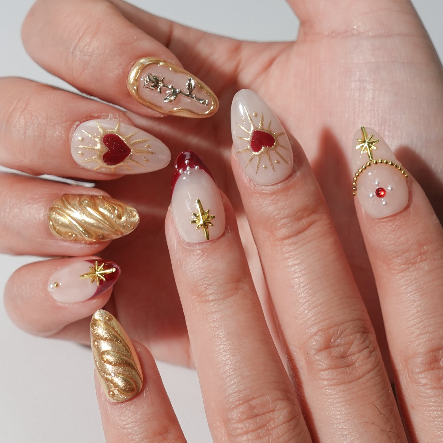 Press - on nails with golden accents, silver owl, deep red and soft pink background.