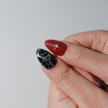 A set of handmade press-on nails featuring deep crimson and black tones, silver chrome details, radiant heart patterns, and a glossy finish. The perfect blend of passion and elegance for a bold, sophisticated look.