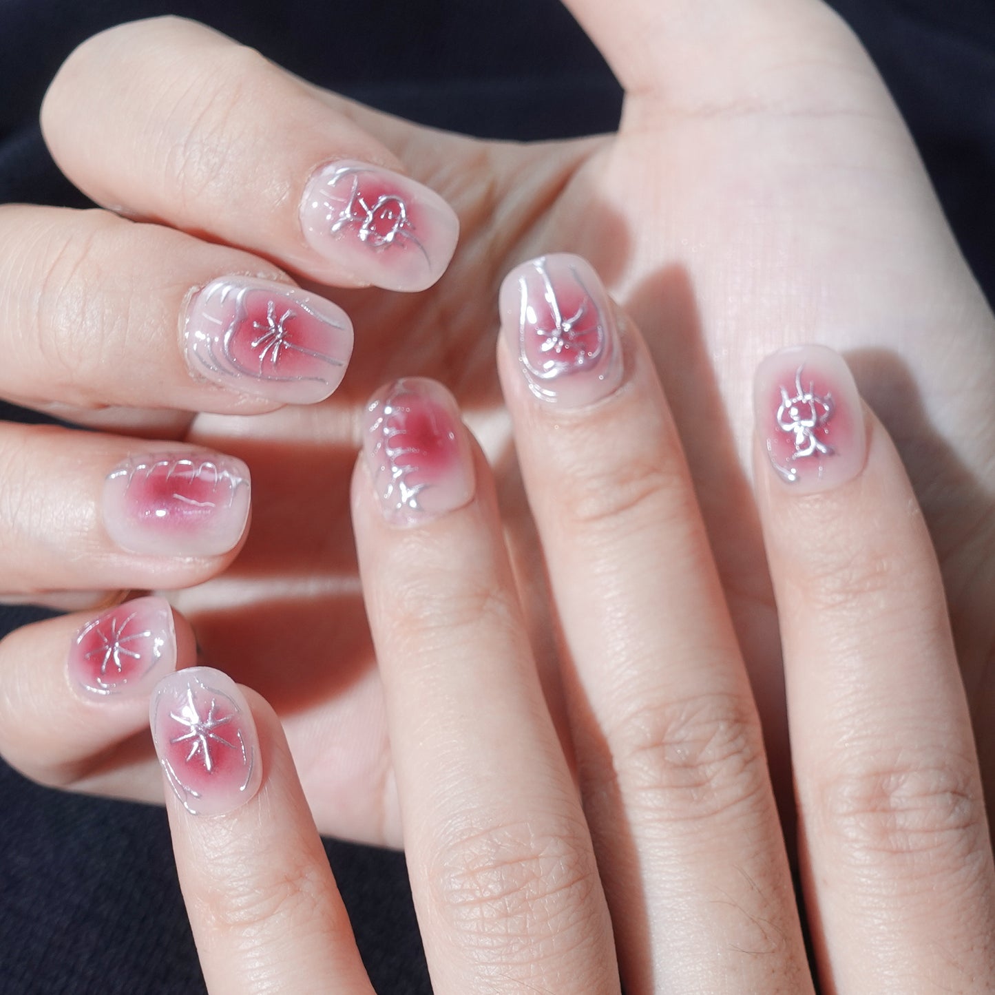 A set of press - on nails with a cracked, blood - red design and metallic silver cracks, giving them a bold and dramatic appearance. The nails are perfect for making a statement at Halloween or gothic - themed events.