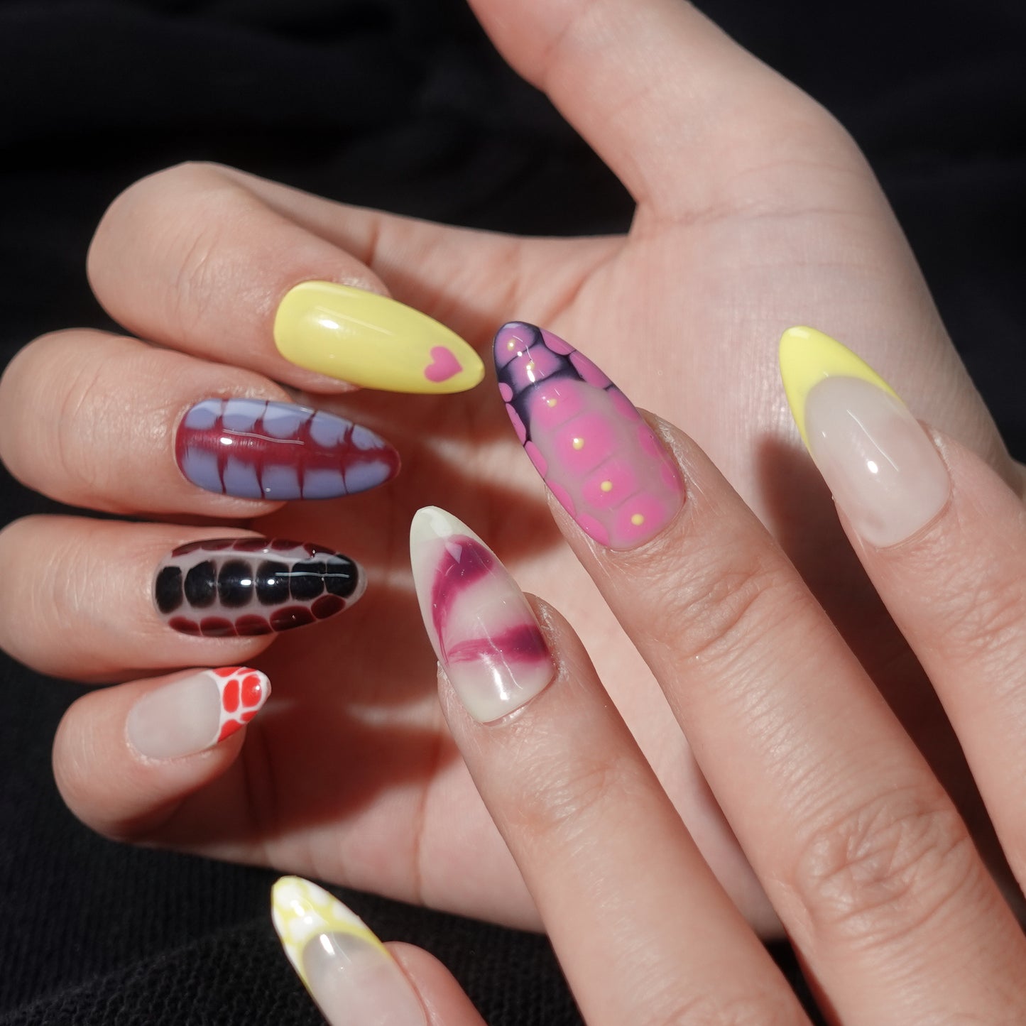 A press-on nail set featuring vibrant snake-skin-inspired patterns in pink, yellow, green, and maroon with glossy gradients, creating a bold and trendy design.