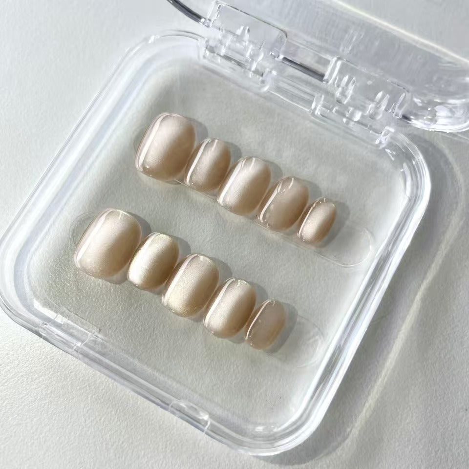 A set of ivory - colored glossy press - on nails neatly arranged in a transparent case, featuring a subtle and smooth finish, ideal for professional or formal occasions.