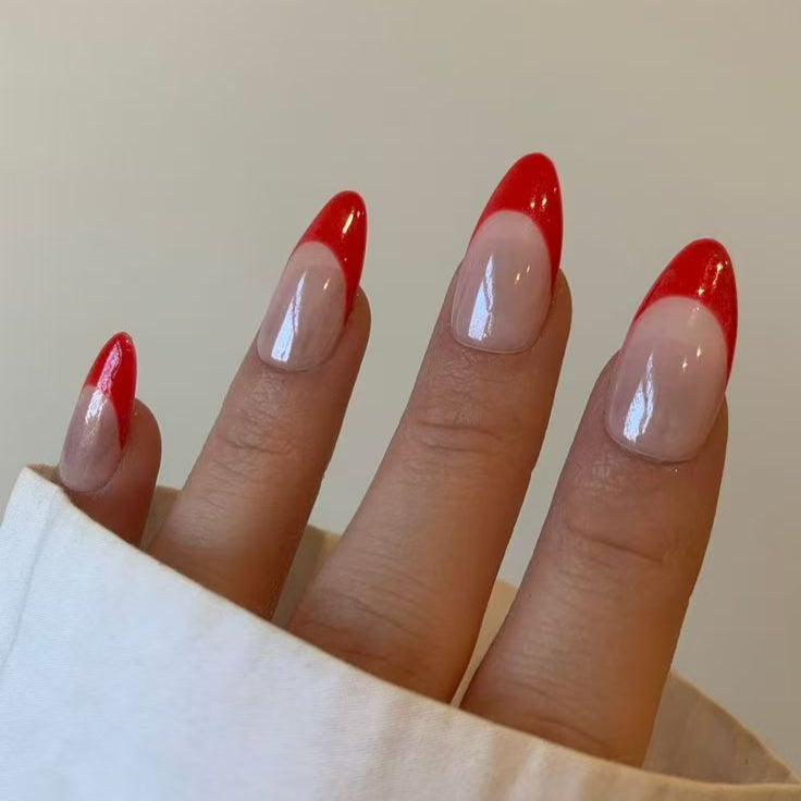 Crimson Chic nail set highlights vibrant red French tips on a neutral base, offering a timeless yet contemporary aesthetic.