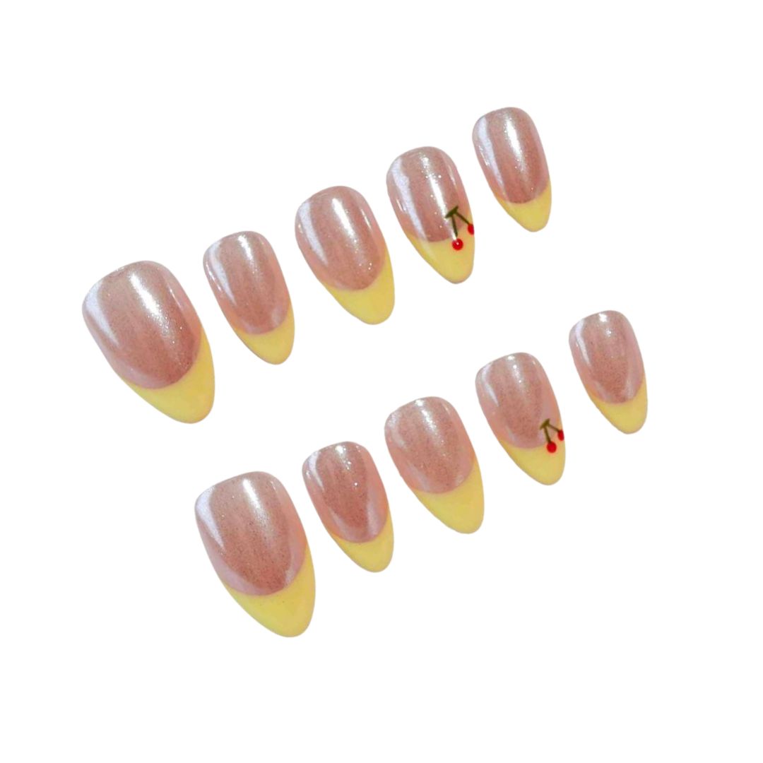 Press-on nails featuring a shimmering pink base, sunny yellow tips, and a charming cherry design, perfect for a cheerful and stylish vibe.