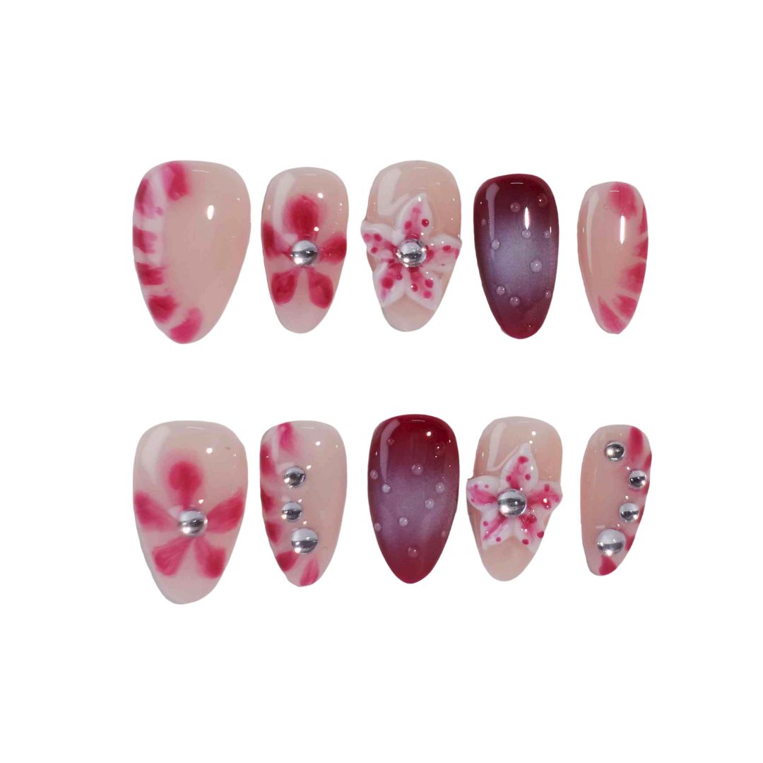 A set of press-on nails featuring a mix of soft pink and deep red tones, adorned with hand-painted floral designs and metallic silver embellishments. These nails create a romantic and chic aesthetic, ideal for evening events or celebrations.